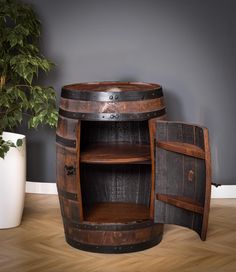 a wooden barrel shelf next to a potted plant on top of a hard wood floor