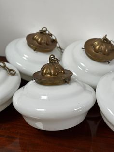 four white dishes with brass bells on them