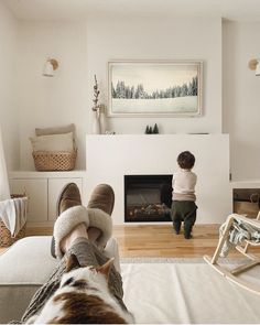 a person sitting on a couch in front of a fire place with their feet up