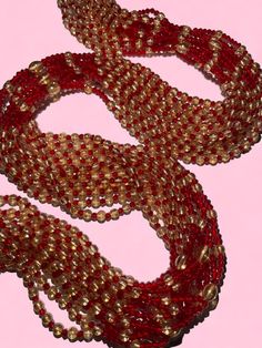 two red and gold necklaces on a pink background