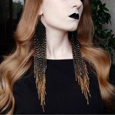 a woman with long red hair wearing black and gold makeup is shown in front of a plant