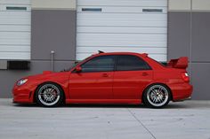 a red car parked in front of a garage