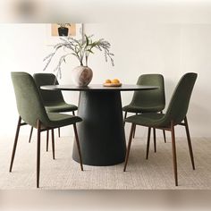 a round table with four chairs around it and a vase on top of the table