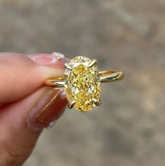 a yellow diamond ring being held in someone's hand with the engagement band on