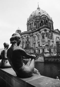 black and white photograph of statues in front of an old building with a dome on top