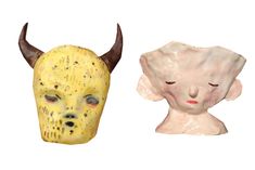 two masks with horns on them are next to each other, one in yellow and the other in white