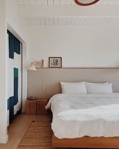 a bed with white sheets and pillows in a bedroom