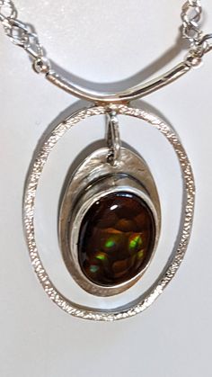 "Mexican Opal Necklace, Orange, green and gold flash in the brown Mexican opal gemstone set in an open oval of sterling silver in a one of a kind necklace. The shimmering colors make this special gem well worth a second and third look. The 20\" double diamond chain has a hand made toggle clasp for ease in wear--no tiny spring clasp to struggle with here. Pendant size overall is 1.8\" high by 1.12\" wide, hanging from a 1 inch bar. Total weight is 0.6 ounces!" Brown Oval Gemstone Jewelry, Artisan Oval Hallmarked Jewelry, Brown Oval Jewelry For Anniversary, Oval Brown Jewelry For Anniversary, Amber Oval Necklace With Large Pendant, Unique Oval Cabochon Jewelry, Amber Cabochon Oval Pendant Jewelry, Artisan Oval Silver Jewelry, Amber Oval Pendant Jewelry, Hallmarked