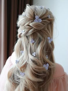 a woman with long blonde hair and purple flowers in her hair is shown from the back