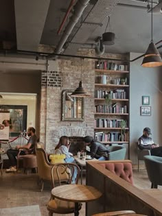 people sitting at tables in a restaurant with lots of bookshelves on the wall