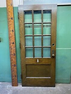 an old wooden door with glass on the front and side panels, next to a ruler