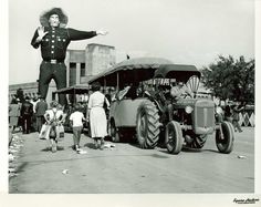 an old black and white photo of people standing in front of a tractor with a man on it