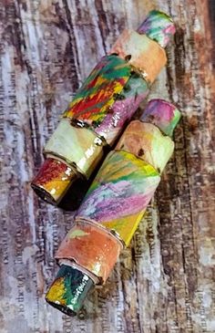 three colorful rolled up paper tubes sitting on top of a wooden table next to each other