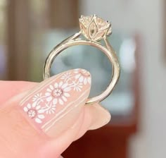 a woman's hand holding a ring with flowers on it