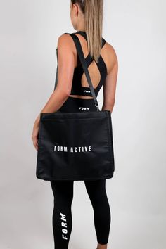 a woman in black sports bra and leggings holding a gym bag with the words form active printed on it