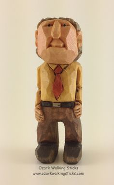 a wooden carving of a man wearing a tie and standing with his hands in his pockets