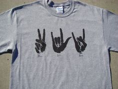 two hands making the peace sign with their fingers on a gray t - shirt sitting on concrete