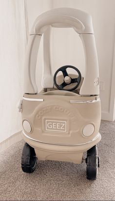 an electric vehicle with steering wheel on carpeted floor next to white wall and curtains