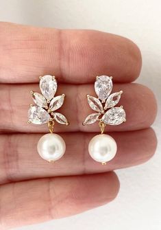 a pair of white pearls and gold leaves earrings