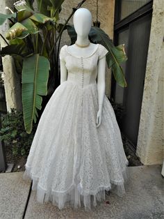 a mannequin dressed in a white dress on display at a storefront window