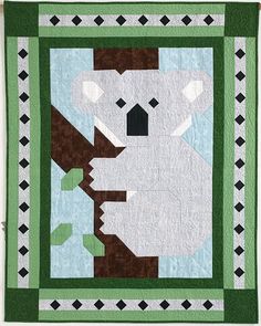 a quilt with a koala bear hanging from it's side and green border