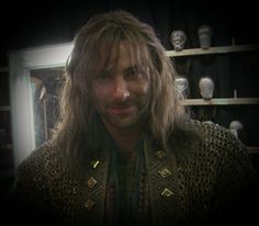 a man with long hair standing in front of shelves