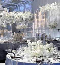 a room filled with lots of tables covered in white flowers and centerpieces on top of each table