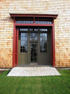 the front door of a house with two windows and brick walkway leading to it's entrance