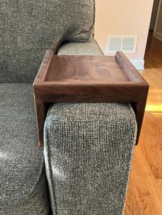 a small wooden tray sitting on top of a gray couch next to a footstool