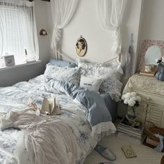 a bed with blue and white comforters in a bedroom next to a dresser, mirror and window