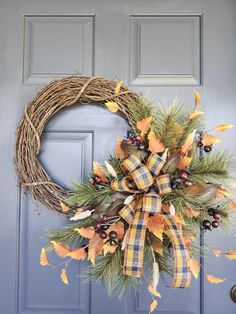 a wreath on the front door with leaves and berries hanging from it's side