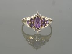 This gorgeous amethyst ring is sure to please! It is crafted of 18k yellow gold and features a stunning colored natural amethyst. This ring also features tiny round brilliant cut diamond accents on the top and bottom of the face. This would make a great Valentines Day, February Birthstone, or Anniversary gift. This ring will be shipped in a brand new gift box. RING SIZE: 7.25 (Sizable by your local jeweler) Metal: 18k Yellow Gold (Verified by acid test) Gemstone: 1 Marquise Natural Amethyst (app Heirloom Purple Rings With Accent Stones, Formal Purple Diamond Birthstone Ring, Fine Jewelry Amethyst Ring With Accent Stones, Multi-stone Amethyst Ring In Yellow Gold, Yellow Gold Amethyst Diamond Ring With Accent Stones, Heirloom Yellow Gold Amethyst Ring With Accent Stones, Marquise Amethyst Jewelry With Accent Stones, Yellow Gold Amethyst Gemstone With Accent Stones, 14k Gold Purple Sapphire Ring With Accent Stones