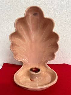 a large shell shaped vase sitting on top of a red table