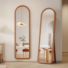 two large mirrors are next to each other in a room with white walls and wood flooring