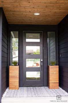 a black front door with two planters on the side