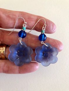 "Beautiful light sapphire blue or royal blue sea glass flowers are the feature of these pretty dangle earrings. Large 1\" sea glass flower is accented with contrasting shades of royal blue, teal and aqua blue sea glass rounds. Earrings are made of cultured tumbled sea glass and wire wrapped in German silver plated jeweler's wire. They hang from silver plated ear wires. Light sapphire blue earrings measure 2\" long and royal blue are 2 1/4\" long. Also available in Sterling silver. Listing is for Blue Flower Shaped Earrings For Summer, Blue Flower-shaped Summer Earrings, Blue Flower Charm Drop Earrings, Blue Flower Earrings For Summer, Blue Sea Glass Nickel Free Earrings, Blue Sea Glass Dangle Jewelry, Blue Sea Glass Nickel-free Earrings, Nickel-free Blue Sea Glass Earrings, Blue Flower Earrings Nickel Free