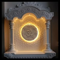 an illuminated clock with the word om on it's face in front of a wall