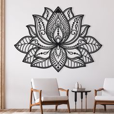 two chairs and a table in front of a wall with a large metal flower on it