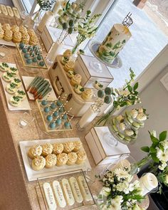 a table filled with lots of desserts and flowers on top of each other in front of a window