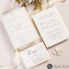 the wedding stationery is laid out on top of the table with white flowers and greenery