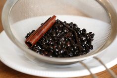 a bowl filled with black beans and a hot dog in it's mouth on top of a white plate