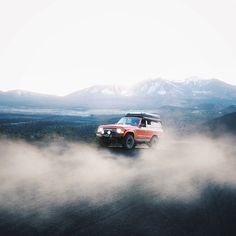 an suv driving through the clouds in the mountains