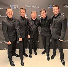 four men in suits posing for the camera