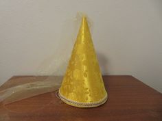 "This is a new Deluxe Princess Cone hat. The hat is made with gorgeous bright yellow or goldenrod satin eversong brocade stretched over a cardboard frame, so it holds its shape very well. It is trimmed with beautiful braid or sequins and has a veil made with tulle.  It has an adjustable elastic to hold it in place Available in three sizes.    Small is approximately 9-1/2\" tall with a 17-1/2\" circumference around the base.   (suggested for toddlers age 1 to 3)  Medium is approximately 11-1/2\" tall with a 21\" circumference around the base.   (suggested ages 3 and up)  Large is approximately 12-1/2\" tall with a 24\" circumference around the base.  (suggested for adults)    Suggested ages are exactly that.  Suggestions.   It depends on how you want to wear your hat Please note:  The hats Princess Cone Hat, Cone Hat, Dresses Materials, Princess Hat, Cardboard Frame, Yellow Satin, Beautiful Braids, Toddler Age, Costume Hats