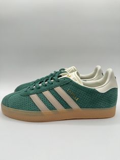 Elevate your sneaker game with these Adidas Men's Gazelle Originals in Size 9. The green and beige colorway, featuring a low top shoe shaft style and lace-up closure, is perfect for any occasion, whether it's activewear or just a stylish look. The shoe width is standard, and the size code is IF7154. These sneakers are part of the Adidas Gazelle product line, and they are designed for walking, running, and jogging. They were manufactured in 2024, and they are not vintage or customized. The shoe is made by Adidas, a well-known brand in the athletic shoe industry. These sneakers are perfect for any man looking for a comfortable and stylish shoe. Versatile Sneakers, Athletic Shoe, Sneaker Games, Adidas Gazelle, Stylish Shoes, Men Looks, Stylish Sneakers, Top Shoes, Step Up