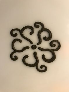 an intricately designed piece of metal on a white surface with the letter s in the middle