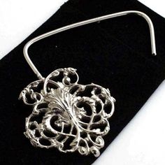 a silver brooch pin sitting on top of a black velvet case