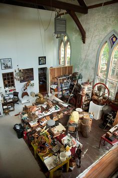 a room filled with lots of clutter next to two large stained glass window windows