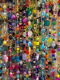 many different colored beads are hanging on the wall