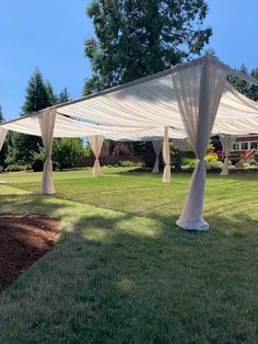 an outdoor wedding ceremony with white draping on the grass and trees in the background